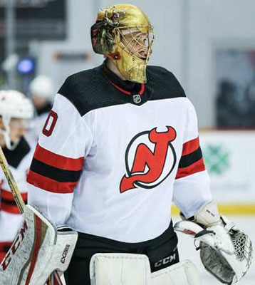 New Jersey Devils goaltender Akira Schmid, back, makes a glove